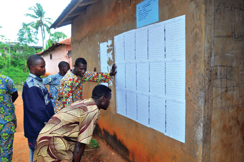 Voters look for their names on voter registration lists outside a polling station in Benin