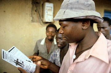 African man reading an AIDS education pamphlet in Uganda