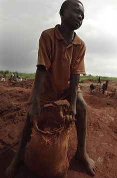 A 13-year-old boy carries a sack of earth and rock at a diamond mine