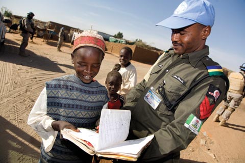 UNAMID officer looks over a student's school work at a North Darfur camp for displaced people