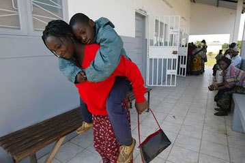 A woman carries her son from a Mozambican health clinic