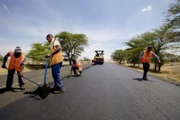 Workers take measurements while laying the tarmac on a new road being built near Arusha, Tanzania. Africa needs funds for such development projects. Panos/Frederic Courbet