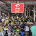 An advertisement for a mobile phone money transfer company hangs over stalls of fruit and vegetables at a covered market in Kigali, Rwanda. Photo: Panos/Sven Torfinn