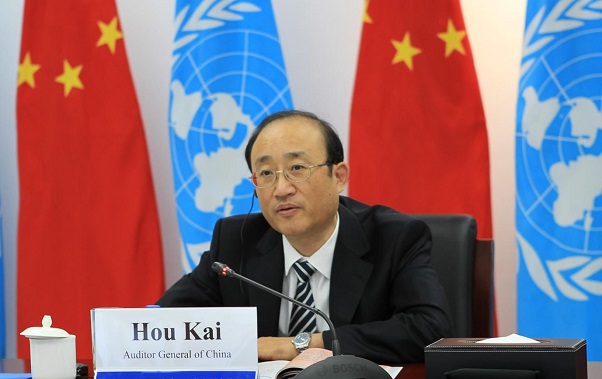 Mr. Hou Kai seated with the flags of the United Nations and China behind him