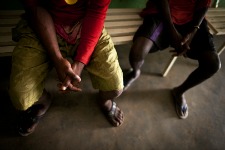 Image of two individuals sitting on a bench showing their hands and feet only