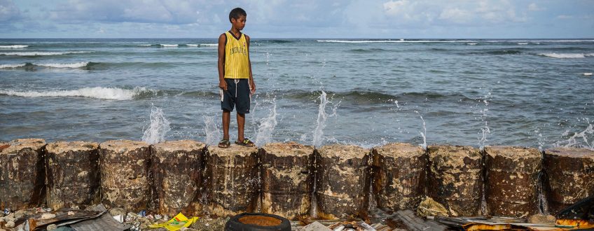 © UNICEF/Vlad Sokhin A boy stands on a seawall that protects his family home from the rising seas in Majuro Atoll in the Marshall Islands.