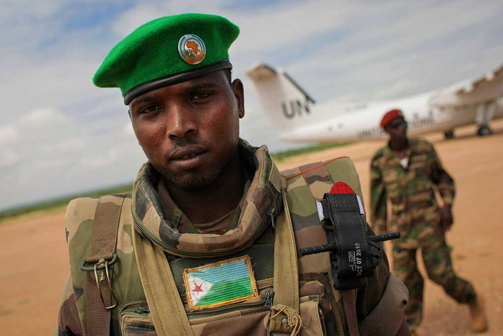 A soldier of the Djiboutian Contingent serving with the African Union Mission in Somalia (AMISOM) stands guard as a United Nations aircraft prepares for take-off from Belet Weyne Airport. AU PHOTO/Stuart Price