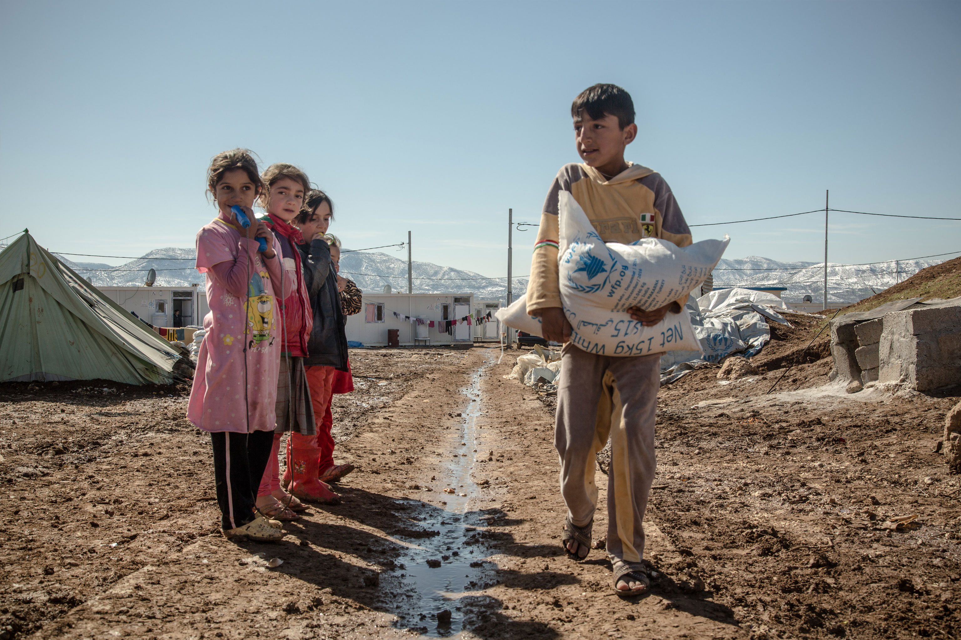 boy carries a sack of food while three girls look on