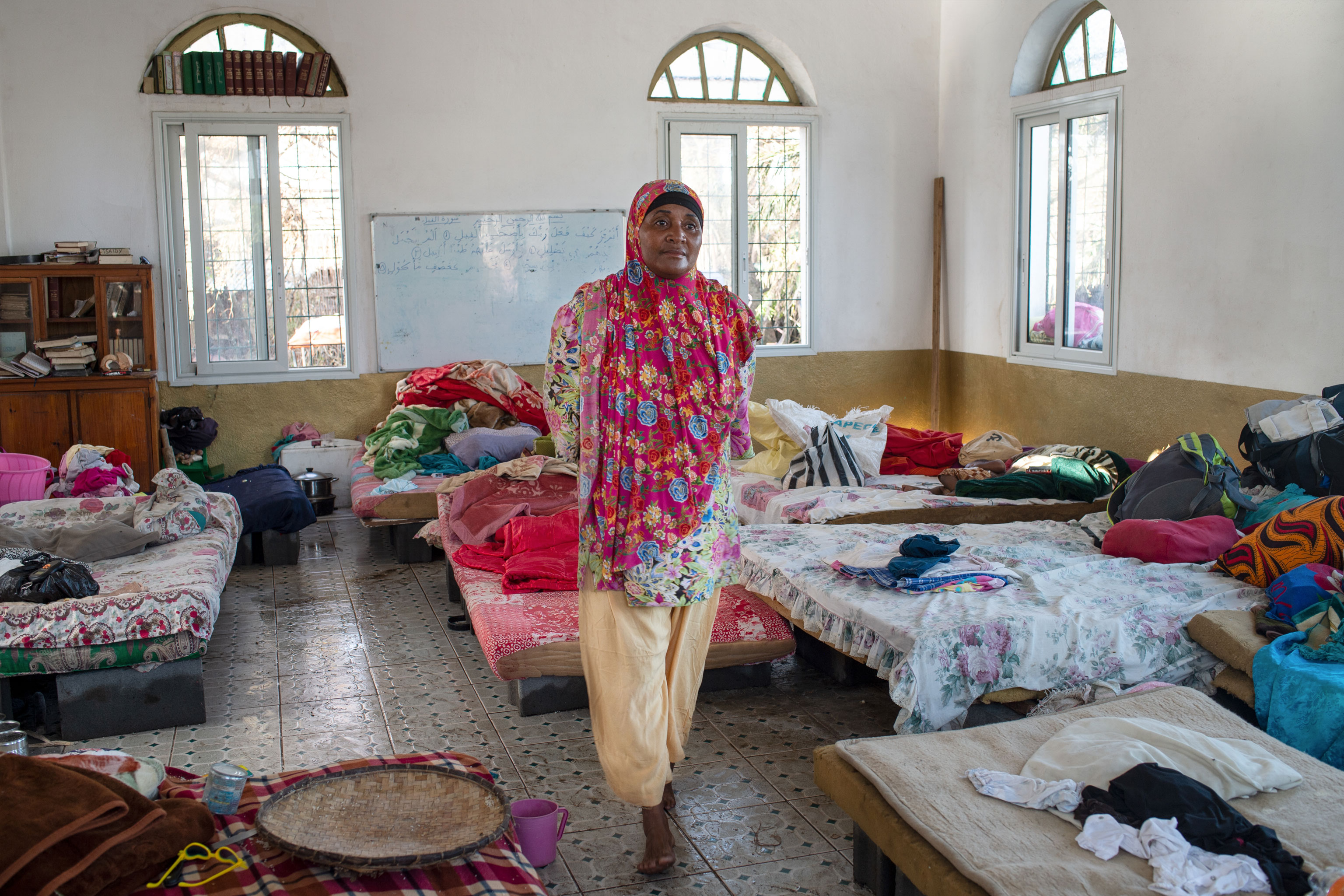 woman walks in a room crouded with beds