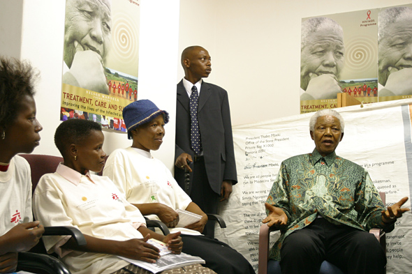 曼德拉在参加于2004年11月举行的一个有关艾滋病毒/艾滋病的会议期间，在一间张贴着艾滋病毒/艾滋病海报的房间内向妇女发表讲话。