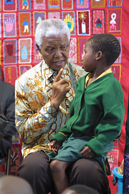 Mandela habla con una niña sentada en su regazo. Tomada durante las reuniones sobre el VIH/SIDA en noviembre de 2004.