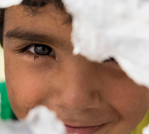 Niño mirando a través de un agujero en una pared de lona