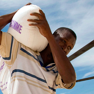 Un travailleur humanitaire transporte un sac d’approvisionnement de denrées alimentaires du Programme alimentaire mondial (PAM) pour des populations touchées par une tempête.