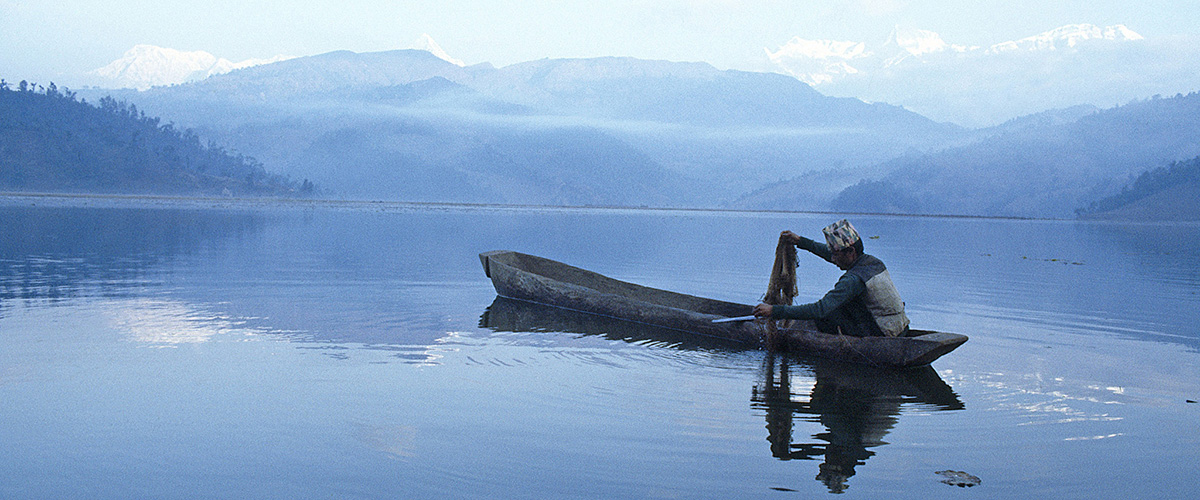 Un pescador en una canoa pescando en el lago Fewa (Nepal).<
