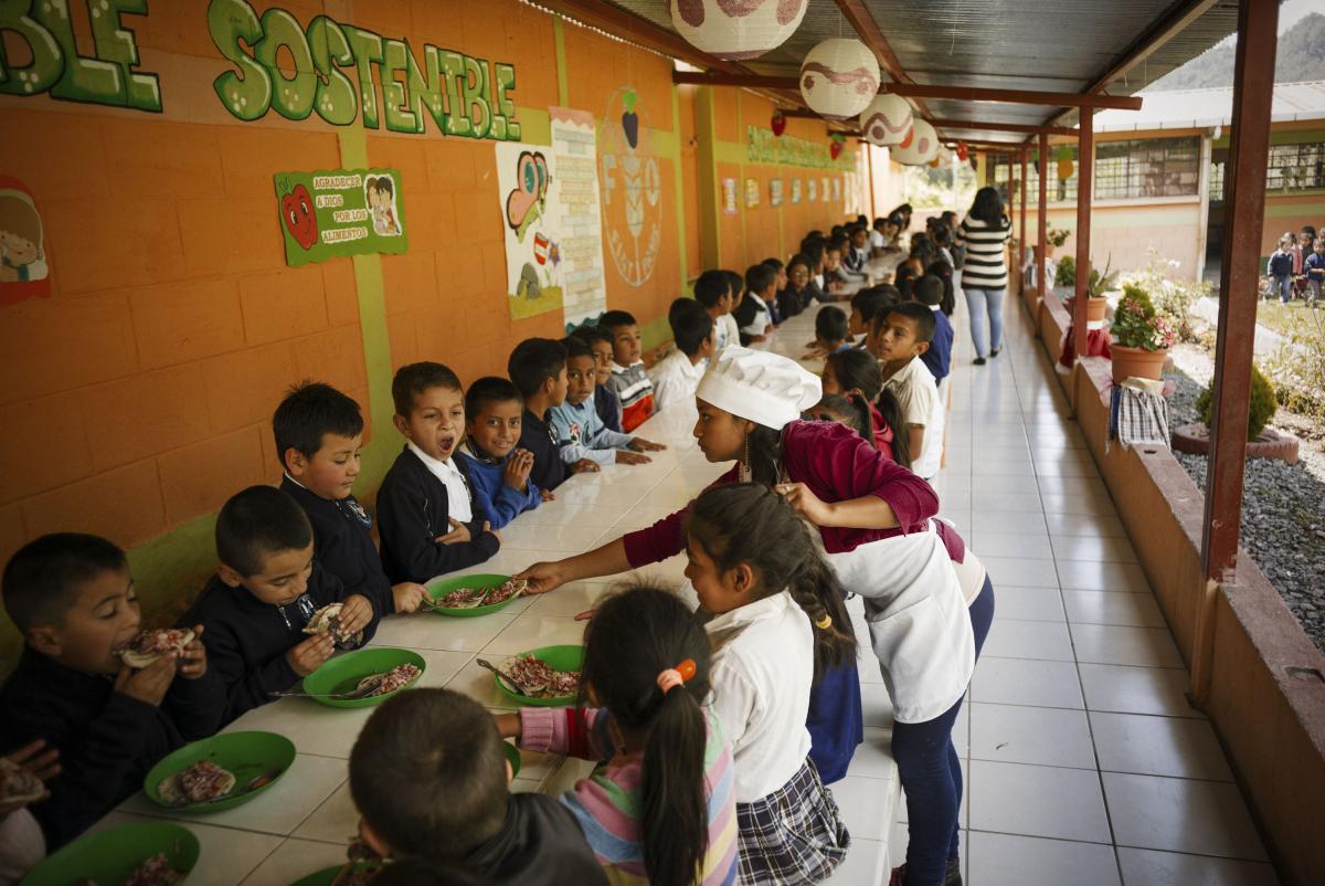 Niños comiendo un almuerzo con alimentos nutritivos y de producción local en una escuela de Guatemala.