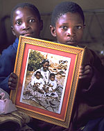 Дети показывают фотографию своих родителей, сделанную незадолго до их смерти от СПИДа (Лесото).  Фото ЮНИСЕФ.