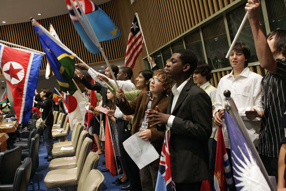 Школьники с флагами государств — членов ООН участвуют 18 сентября в мероприятиях по случаю Международного дня мира.