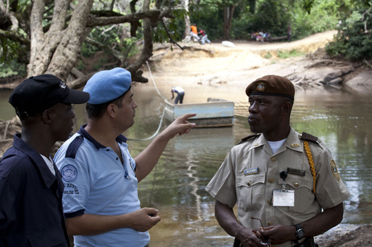 Полицейский ООН из Турции ведет переговоры с представителями либерийской иммиграционной и полицейской службы на границе с Кот-д'Ивуаром, где в первые месяцы 2011 года в попытке найти в Либерии укрытие от боевых действий пересекли реку более 100 000 ивуарийцев. Фото ООН/Стейтон Винтер