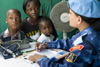 Врач из индийского женского сформированного полицейского подразделения в составе Миссии ООН в Либерии проводит бесплатный медицинский осмотр членов местной семьи, 2009 год. Фото ООН/Кристофер Хервиг
