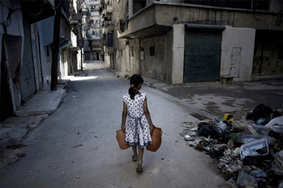 Una niña carga jarras de agua y pasa junto a una pila de deshechos en una calle de Aleppo, Siria. UNICEF/NYHQ2012-1293/Romenzi
