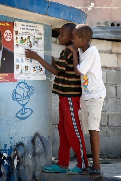 Niños leen un cartel de prevención del cólera en Cite L'Eternel, un barrio pobre de Puerto Príncipe. Foto ONU/UNICEF/Marco Dormino