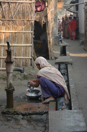 Gender equality and sustainable urbanization: Woman washing utensils by standpipe © UN-HABITAT