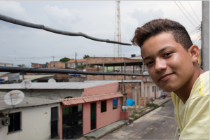 UNICEF Image © UNICEF Brazil/2017/Pereira Marvin Oliveira da Silva looks out onto the street below his home. His father does not like him to be out on the street after school, for fear of bad influences.