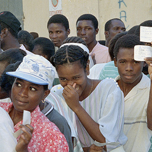 投票者在等待海地历史上（1990年）第一个和平、民主的总统选举的过程中骄傲地展示他们的登记卡。