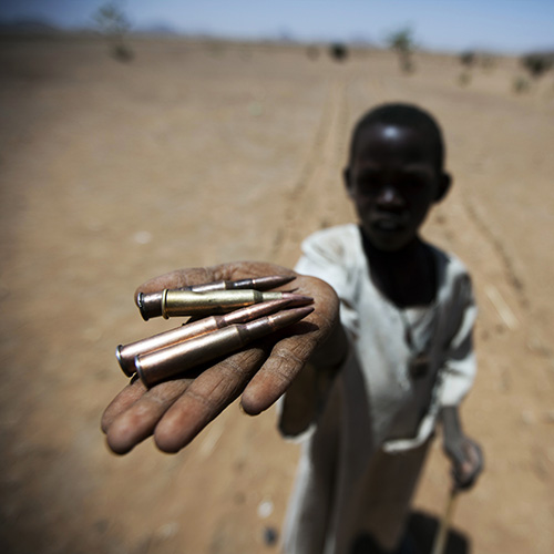 苏丹北达尔富尔州的一名儿童手握从地上捡来的子弹。 联合国图片/Albert González Farra