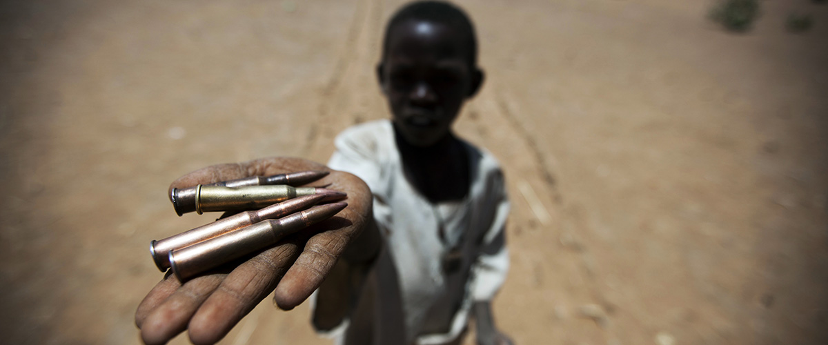 苏丹北达尔富尔州的一名儿童手握从地上捡来的子弹。 联合国图片/Albert González Farra