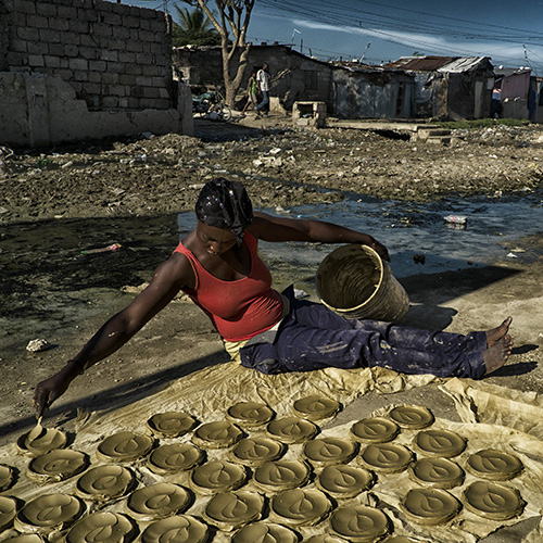 一名海地妇女正在准备做“泥土蛋糕”，也就是用粘土、黄油和盐制成薄片，并用太阳烘烤而成的食品。这一食品已成为海地与极端贫困和饥饿作斗争的象征。 ©联合国图片/Logan Abassi 