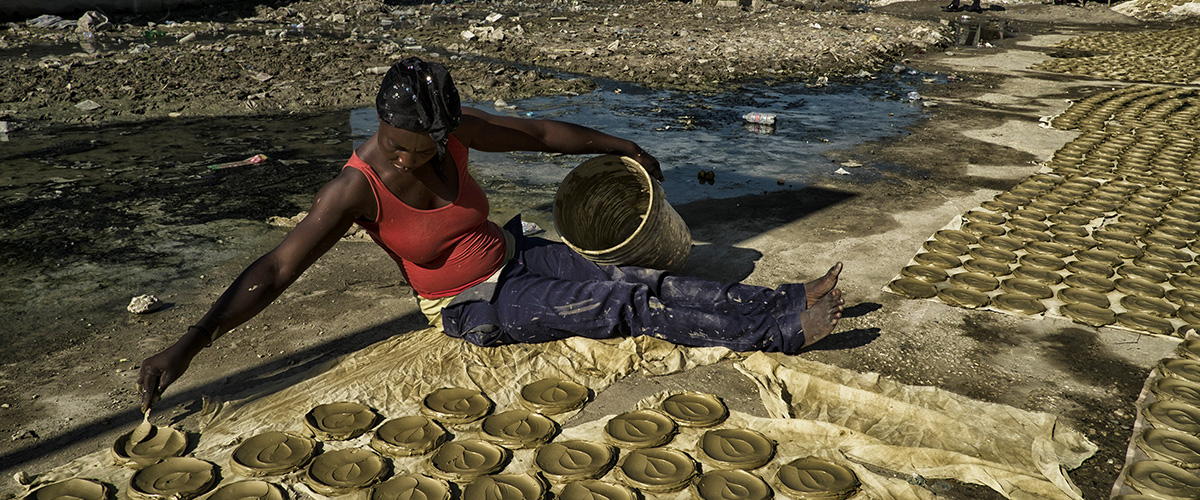 一名海地妇女正在准备做“泥土蛋糕”，也就是用粘土、黄油和盐制成薄片，并用太阳烘烤而成的食品。这一食品已成为海地与极端贫困和饥饿作斗争的象征。 ©联合国图片/Logan Abassi

