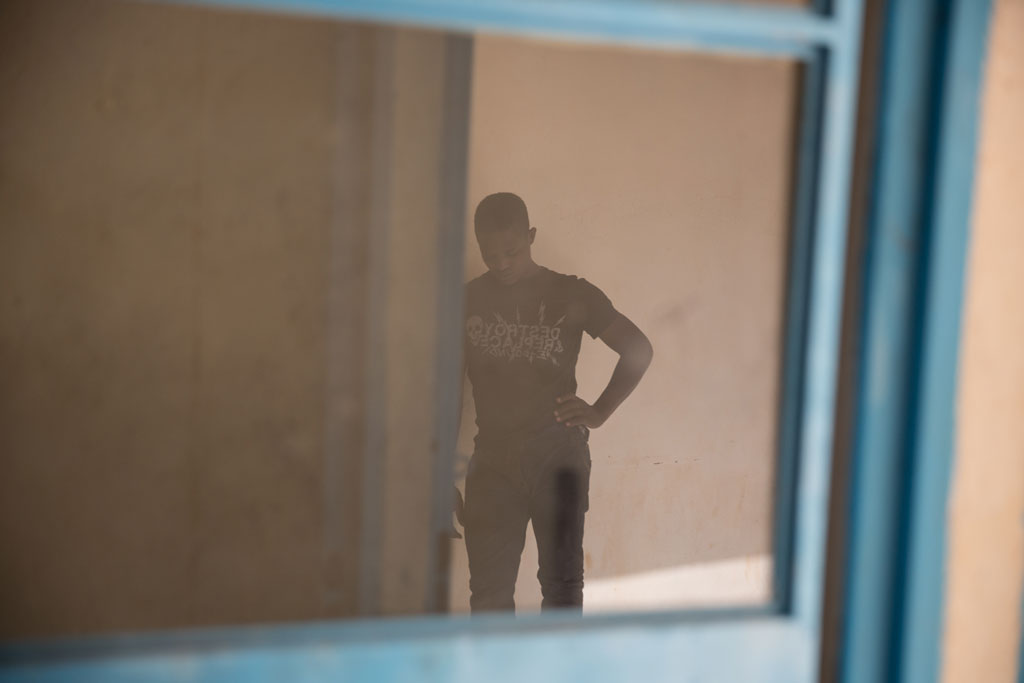 Un jeune homme attend dans un centre de transit de l’OIM à Agadez, au Niger. Photo OIM 2016/Amanda Nero