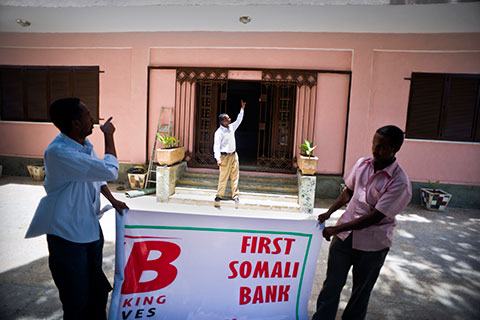 Installing a sign at one of the firstcommercial banks to reopen in Mogadishu