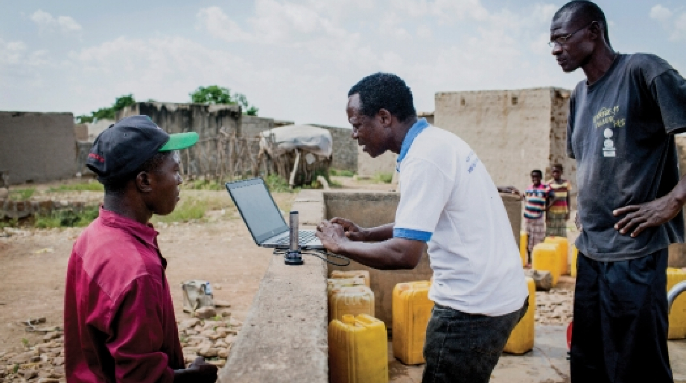 An official checks data from an internet-based water monitoring device at a borehole in Basbedo, Burkina Faso. Photo: Panos/Andrew McConnell