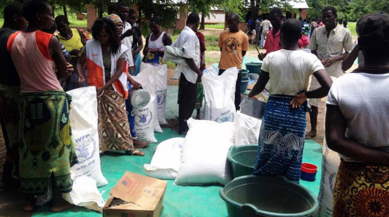 People gather at Mikolongo school in Chikwawa district, Malawi, to receive rations of maize, pulses, oil and fortified corn soya blend from WFP to prevent malnutrition. Photo: WFP/Dannie Phiri