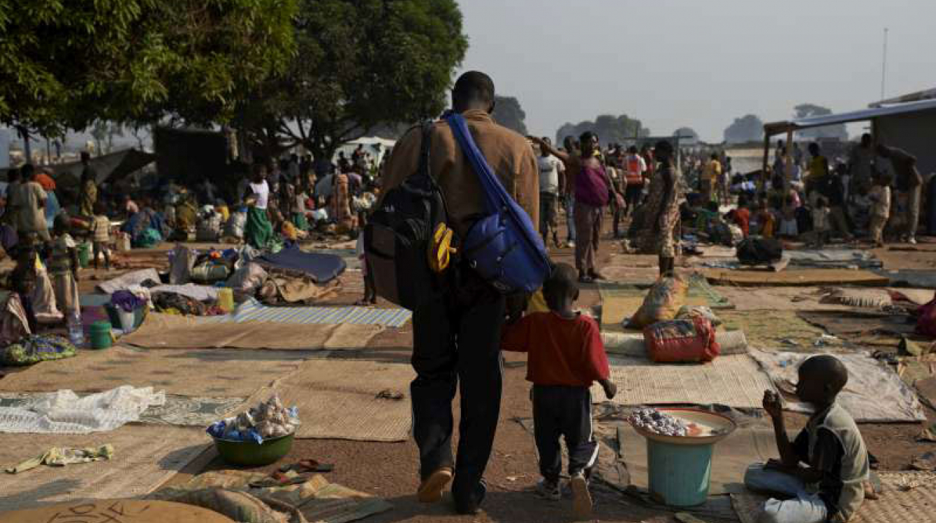 A man and his child walk through a crowded site for internally displaced people in the Central African Republic capital, Bangui, where many people remain at risk. Photo: UNHCR/S. Phelps