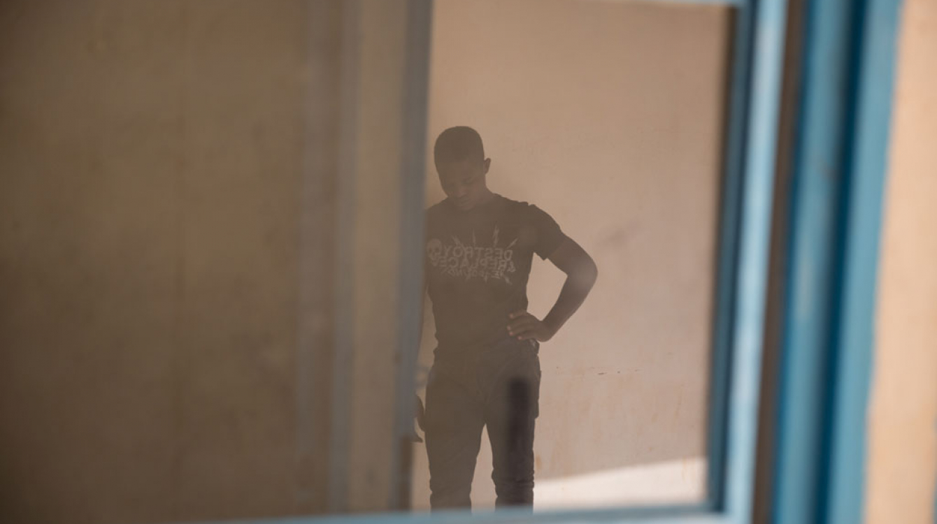 Un jeune homme attend dans un centre de transit de l’OIM à Agadez, au Niger. Photo OIM 2016/Amanda Nero