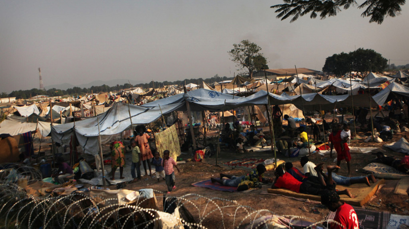 Des enfants et des adultes déplacés dans un camp derrière l’aéroport de Bangui, en République centrafricaine (RCA). 