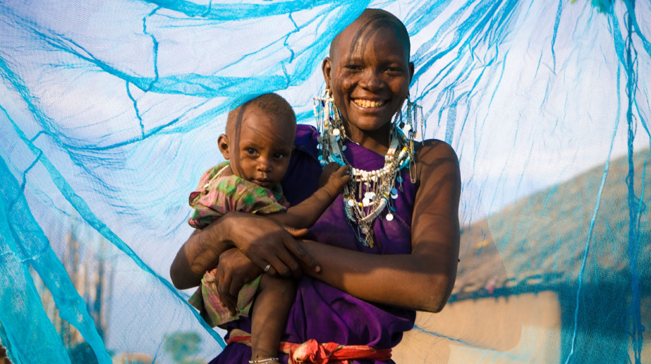 Une mère souriante avec son jeune garçon sous un filet insecticide, à Arusha, en Tanzanie. 