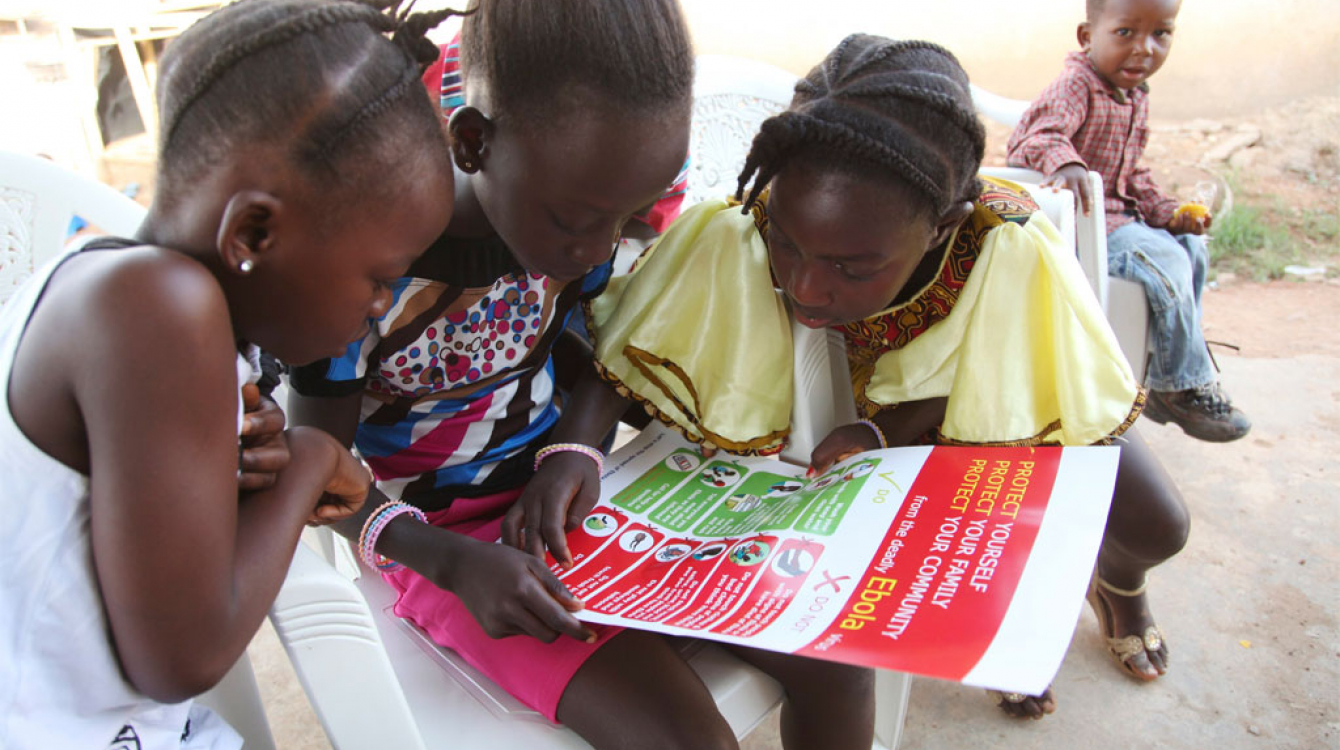 Girls in the city of Voinjama look at a poster that displays information and illustrations about how to prevent the spread of Ebola. Photo: UNICEF/2014/Liberia/Jallanzo