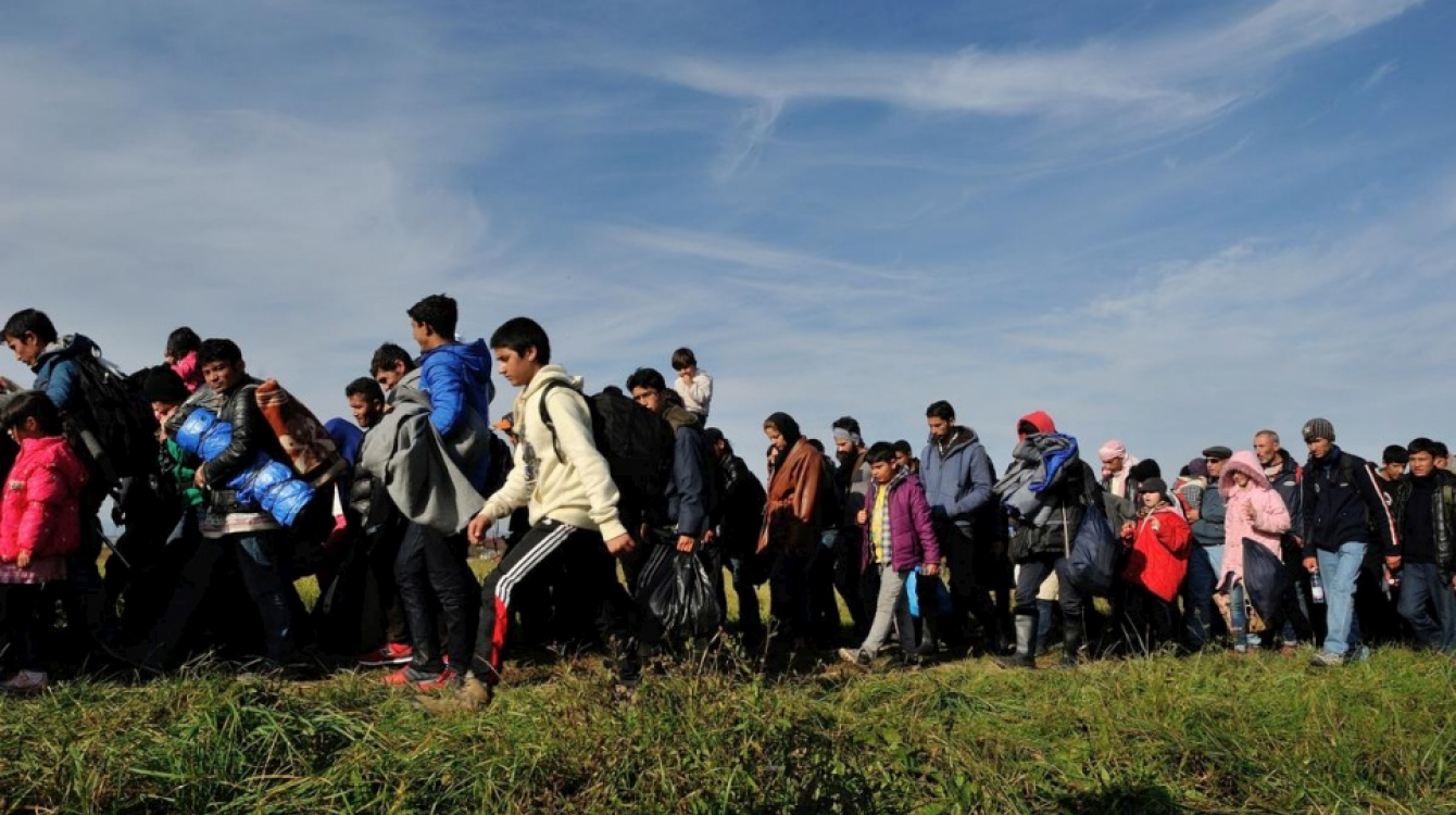 A column of refugees and migrants is walked across fields by police in Slovenia in this October 2015 file photo.  © UNHCR/Mark Henley