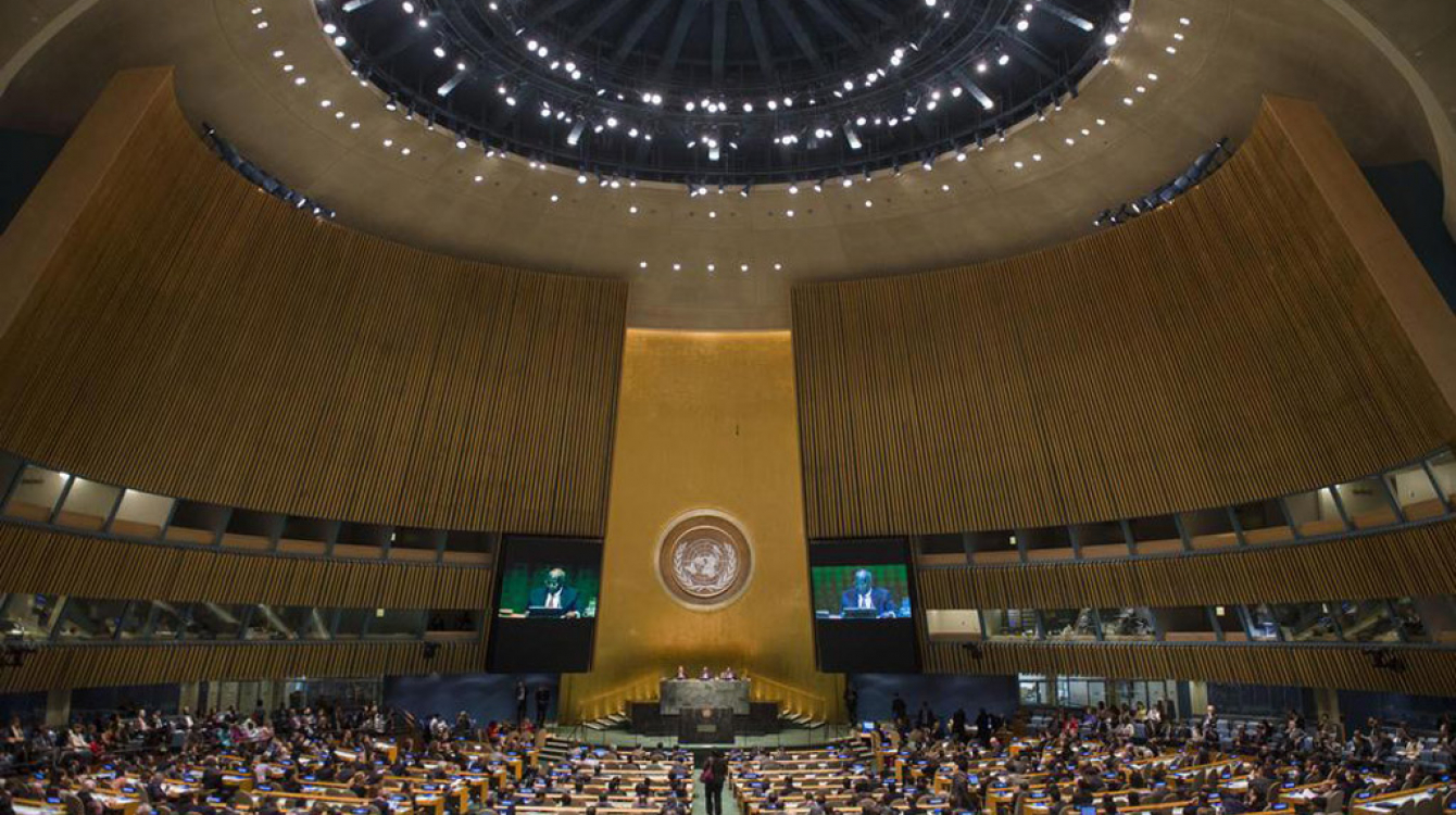 A wide view of the General Assembly Hall as President of the 69th session of the Assembly, Sam Kahamba Kutesa (on screens), makes his opening address. UN Photo/Amanda Voisard