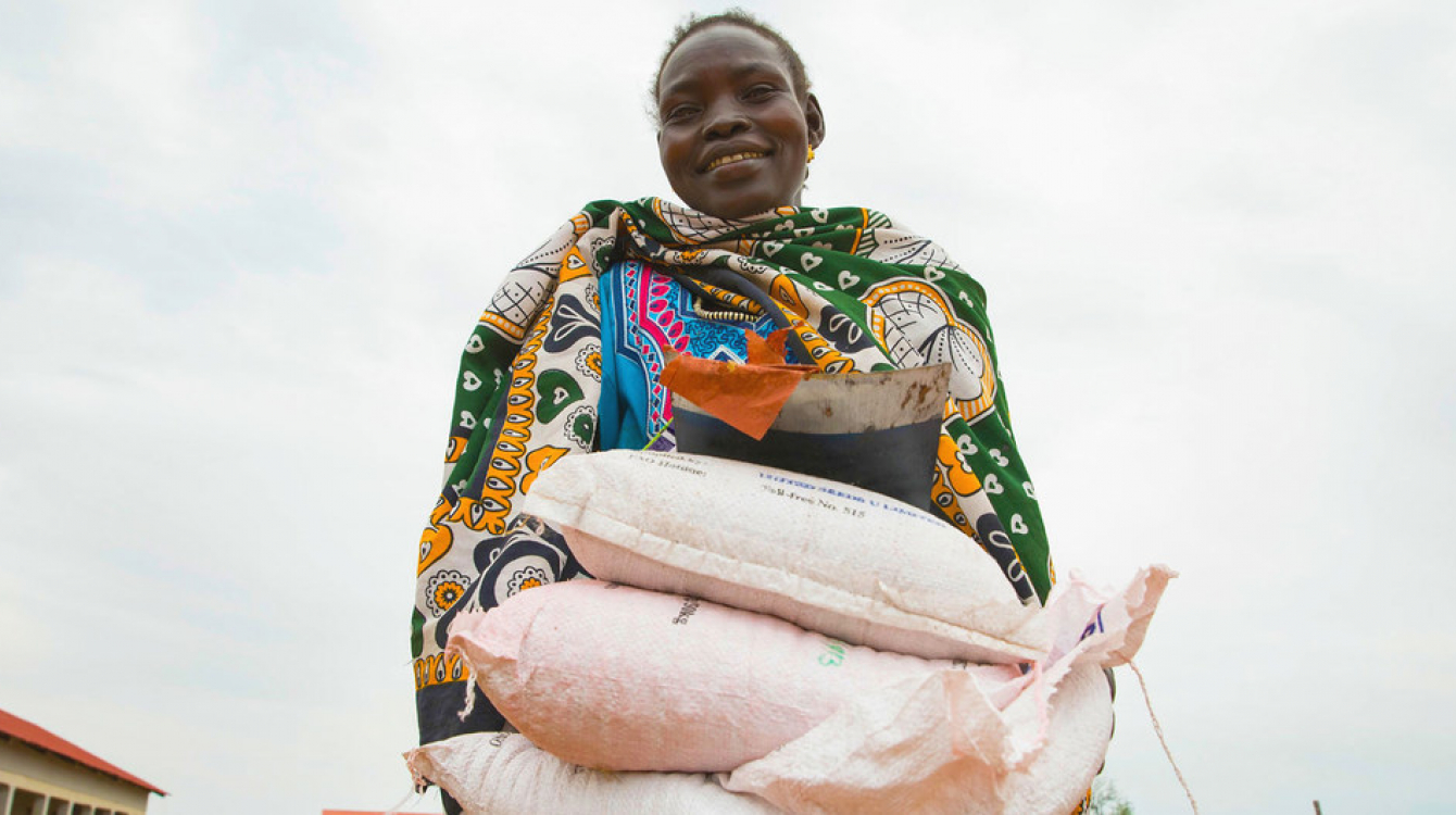 A woman carries sacks of seeds distributed to families in South Sudan during the COVID-19 pandemic.