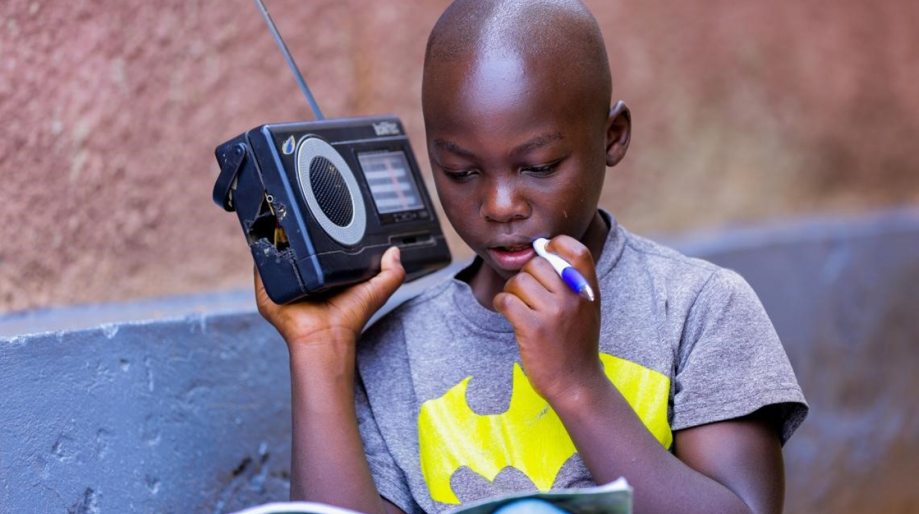 Igihozo, 11, listens to a lesson on a radio after his school was closed in Rwanda.