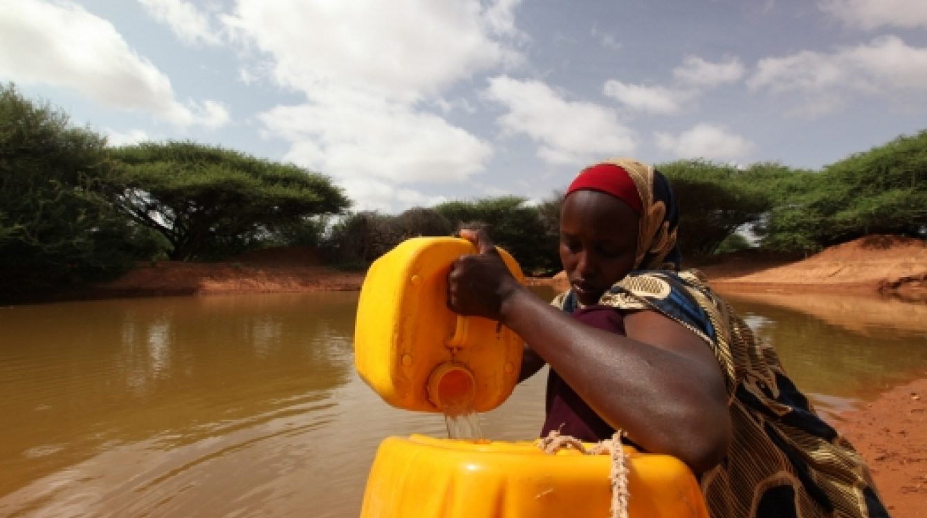 A woman drawing water from a man-made pond in drought-stricken Somali.  Photo: UNDP Somalia