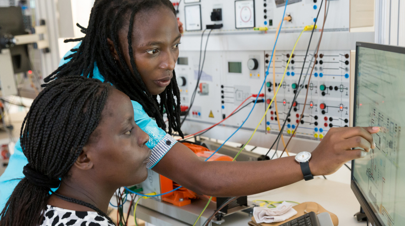 Two students practicing with wind, solar and other models on computer.