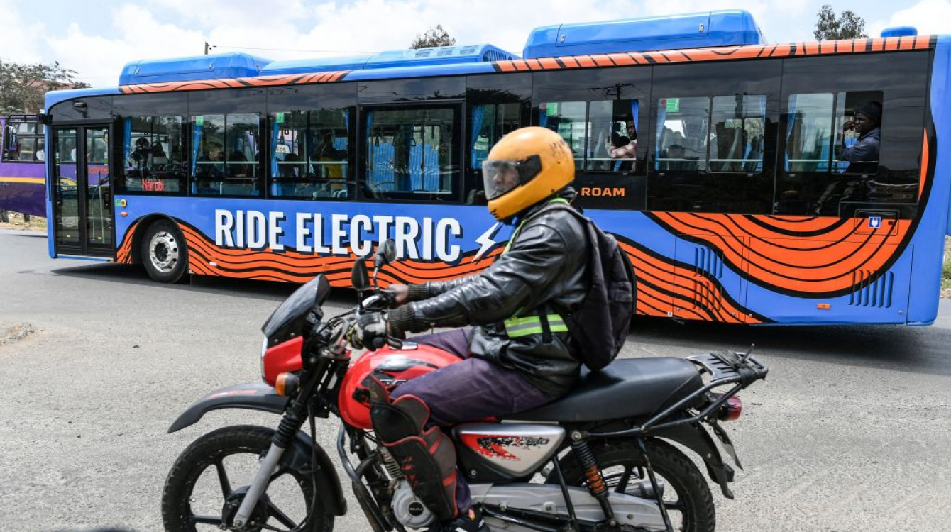 A motor bike rider in Nairobi, October 19, 2022, next to an electric bus 