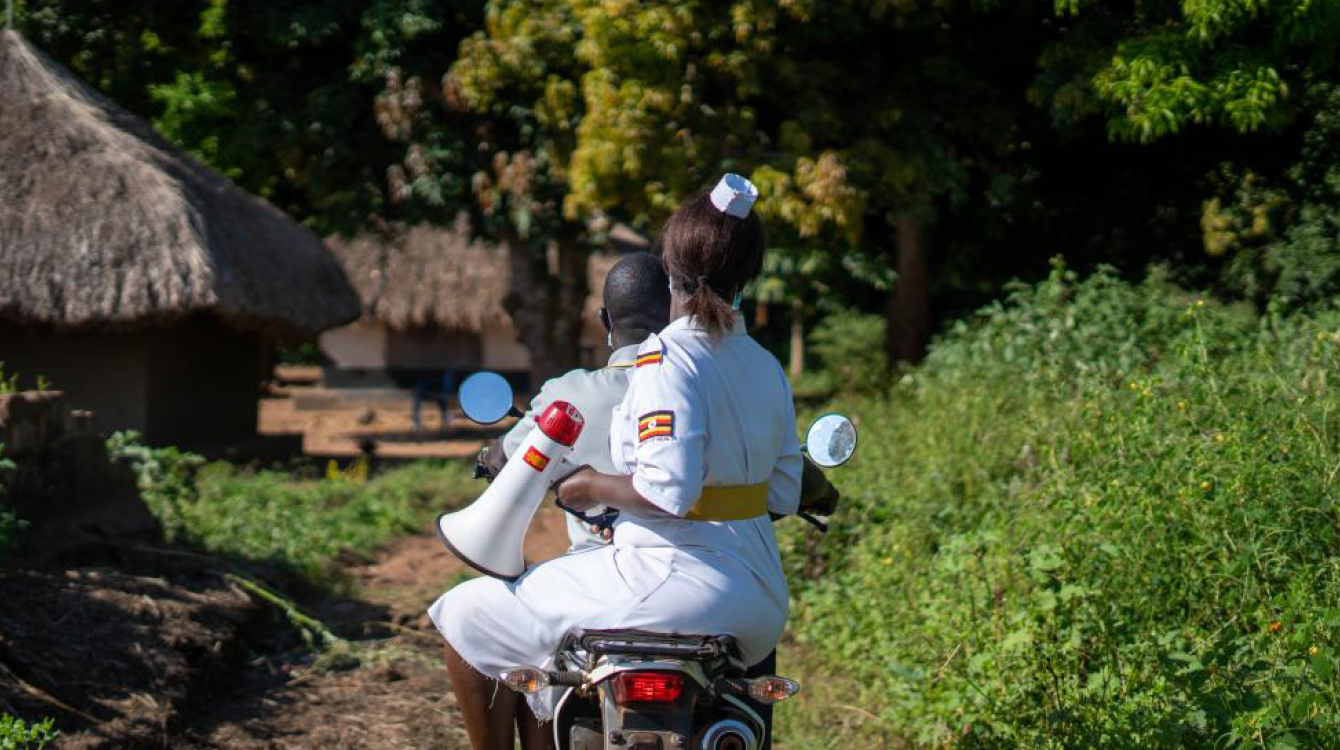 Ugandan healthcare worker on motorcycle with megaphone.