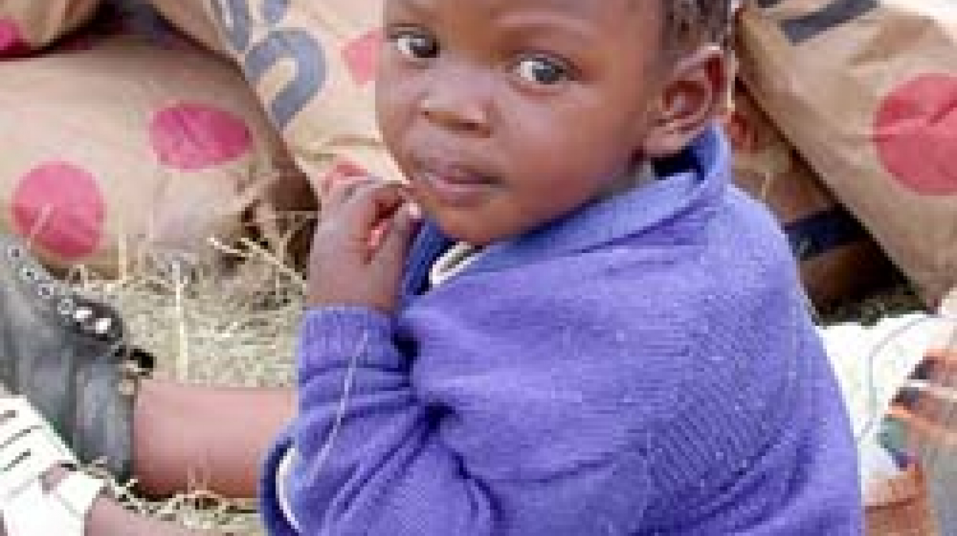 Child sitting amidst sacks of relief grain in Lesotho: Emergency aid is vital, but “just shipping in food is not enough,” says UN Secretary-General Kofi Annan: Poverty and other causes of famine must also be addressed.  Photograph: WFP / R. Lee